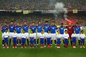 11 members of the Malaysian football team standing side-by-side on the field of a stadium