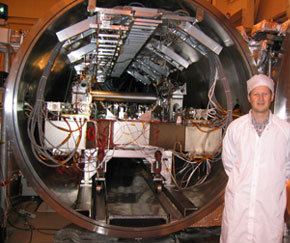 Man in white standing in front of a large machine