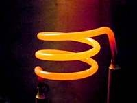 Three helical loops of cylindrical molybdenum disilicide incandesce a vivid orange from heat.