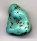A polished, freeform cabochon of turquoise blue with brown dots of matrix inclusions.