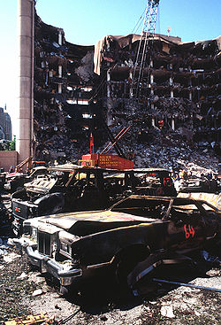 A view of the destroyed Alfred P. Murrah Federal Building from across the adjacent parking lot, two days after the bombing alongside several destroyed parked cars.