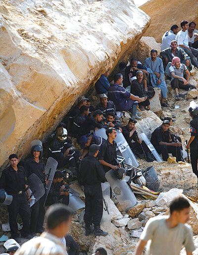 ملف:رجال شرطة يقفون بمعداتهم تحت الصخرة الضخمة التي سقطت على المنازل في الدويقة 2008.jpg
