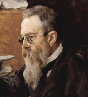 Head of a man with dark greying hair, glasses and a long beard