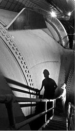A worker stands by the 30 ft. diameter Nevada penstock before its junction with another penstock that delivers water to a turbine.