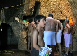 اليهود المتدينون ينتظرون دورهم ليغطسوا في عين جارية ليطهروا أنفسهم طقسياً قبل ساعات من بدء يوم كيپور 27 سبتمبر 2009 في كهف في روابي القدس.
