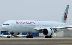 Twin-engine passenger jet on the ground. It is white with "AIR CANADA" in red on its side.