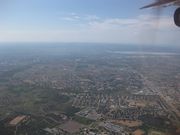 A broad view of the city facing east, the picture taken from a plane. In the middle is a large residential neighborhood. The downtown area and the Gaborone Dam are in the far right towards the horizon. At the bottom of the picture to the left is a large undeveloped area, and to the right is another neighborhood.