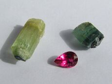 Dark bluish and green or black, rod-like tourmaline crystals emerging from clear quartz holding matrix.