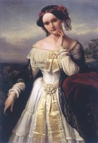 A three-quarter length portrait of a young white woman in the open air. She wears a shawl over an elaborate-long-sleeved dress that exposes her shoulders and has a hat on over her centrally-parted dark hair.