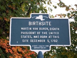A bronze marker with a map of the State of New York at the top, under which is the word Birth site and other text