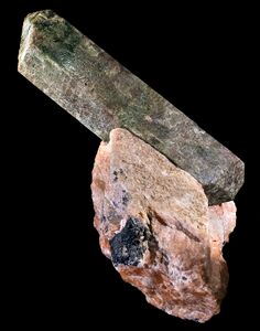 Fluorapatite: Long, prismatic crystal, dull in lustre, protruding, at an angle, from matrix of aggregate-like rock