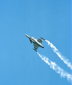 Jet aircraft performing rolls while climbing, revealing its underside. White smoke trail from each wing tip.