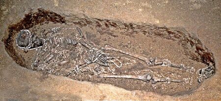 Skeleton in a burial pit, covered in ivory beads
