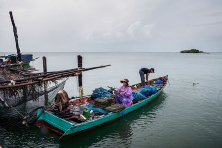 قرويون يعدون شباك الصيد في تشاملانگ كو. القرية هي جزء من امتياز أراضي دارا ساكور الذي أُجـِّر لشركة صينية بشروط غير معتادة.