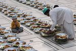 پاكستاني يعد طعام الافطار، في أول أيام رمضان، بينما طفل ينظر، في مسجد في كراتشي، پاكستان، يوم الأحد 23 أغسطس 2009.