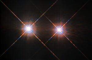 Two white disks side by side, each with coloured fringes and prominent diffraction spikes