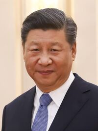 Head shot of Xi Jinping in 2019. He is wearing a black suit jacket, white shirt and a blue necktie.