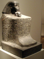 تمثال كتلي لسننموت ورأس ابنة حتشپسوت نفرورع تظهر تحت رأسه. من المتحف المصري ببرلين.
