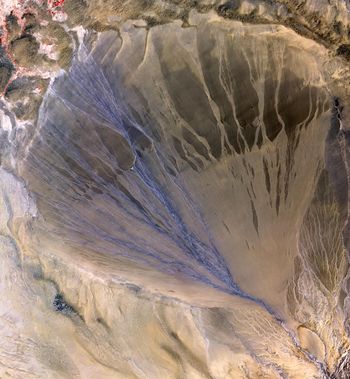مروحة طميية هائلة تفترش الأرض الجرداء بين سلسلتي جبال كون‌لون و ألتون اللتين تشكلان الحد الجنوبي لصحراء تكلامكان في شين‌جيانگ. الجانب الأيسر هو الجزء النشط في المروحة، ويبدو مزرقاً بسبب الماء المنساب في العديد من الغدائر الصغيرة. تصوير: NASA/GSFC/METI/ERSDAC/JAROS/ASTER