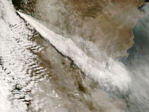 Volcanic ash streams out in an elongated fan shape as it is dispersed into the atmosphere.