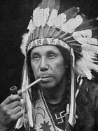 Chief William Neptune of the Passamaquoddy, wearing a headdress and outfit adorned with swastikas