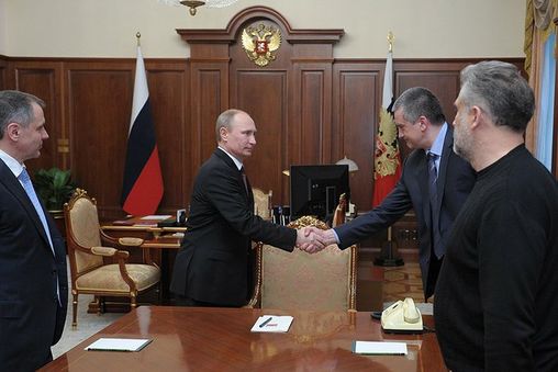 Putin shakes hands with Sergey Aksyonov, de facto Prime Minister of Crimea while Chairman of the Crimean Parliament, Vladimir Konstantinov (left), and Chief of the City Council of Sevastopol, Aleksei Chalyi (right), watch.
