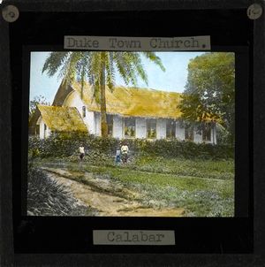 Image of the Duketown Church, Calabar (located within later day Nigeria). Three people stand in front of the white-sided church with a thatched roof. Duketown تقع على نهر كلبار على بعد 50 كم من الساحل.