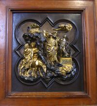 Small bronze sculpture in high relief. The space is crowded with action. At the top of a mountain, Abraham is about to sacrifice his son Isaac, who kneels on an altar. As Abraham wields a knife, an Angel raises his hand to stop the action, and directs him to sacrifice a sheep caught in a bush. At left are two servants and a donkey.