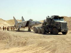 An Iraqi MiG-25RB Foxbat-B found buried under the sand west of Baghdad is towed by an M1070A0