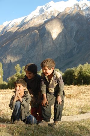Three smiling young boys, with trees and a mountain in the background