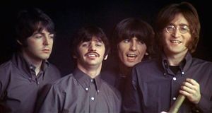 The Beatles, wearing identical dark-grey button-down shirts. They are clean-shaven, except for Starr, who has a mustache. Lennon, wearing mutton chops, holds a folded telescope. All are smiling, except for McCartney, who looks pensive.