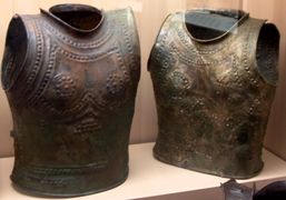 Bronze breastplates, each composed of two shells, rivetted together on one side and closed with a hook on the other, illustrating the evolution from bronze to iron working (circa 950 BC to 780 BC).