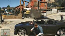 The player character crouched behind a vehicle while in combat. The head-up display elements are visible on-screen.