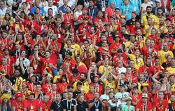 About a hundred Belgian football wearing mainly red shirts sitting in the stadium