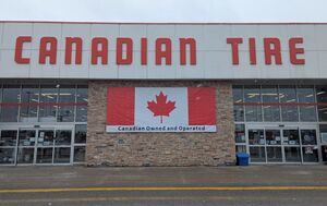 The facade of a Canadian Tire with a banner reading "Canadian owned and operated" on a Canadian flag