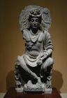 Maitreya, seated on a throne in the Western manner, with Kushan devotee. 2nd century Gandhara.