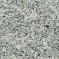 The polished face of a granite slab showing an even pattern of white, greenish and black crystals.