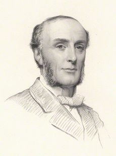 A balding man with prominent sideburns, wearing a dark suit and white shirt.