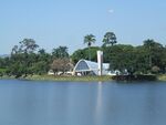 White modernist building in front of a lake.
