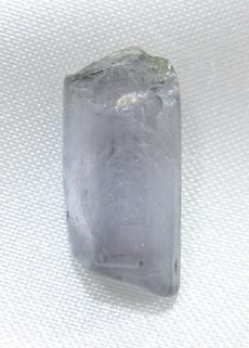 A long crystal of light purple sillimanite on a white background.