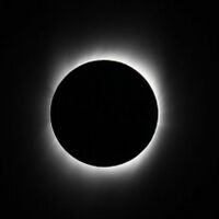 A blackish circle outlined in hazy streaks of white emanating from the circle to the edges of the image all on a solid black background