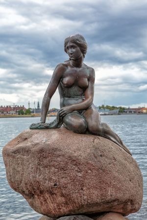 تمثال لعروس البحر جالسة على صخرة محاطة بالماء.