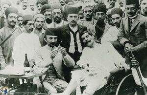 Doctor treating an injured man, with a crowd of standing men behind them
