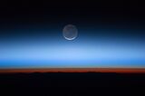 This image shows the Moon at the centre, with the limb of Earth near the bottom transitioning into the orange-colored troposphere. The troposphere ends abruptly at the tropopause, which appears in the image as the sharp boundary between the orange- and blue-colored atmosphere. The silvery-blue noctilucent clouds extend far above Earth's troposphere.