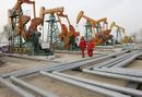 Employees walk near oil pipes at a refinery in Daqing, Heilongjiang province November 6, 2009. China denounced as protectionist new U.S. anti-dumping duties on steel pipes on Friday and called for Washington's swift recognition that it is a market economy, a week before a visit by U.S. President Barack Obama.