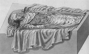 An open tomb seen from the side in a 45-degree angle from the ground. The corps, with his head to the left, is dressed in fine funeral attire, wears a coronet and holds a sceptre in each hand.