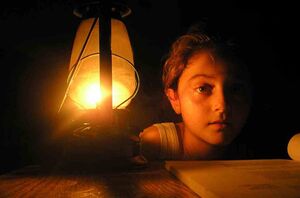 طفلة في منزل مظلم على ضوء مصباح.jpg