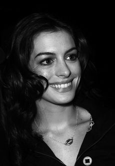 Anne Hathaway is smilin to her right in the black-and-white picture.