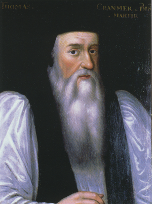 Portrait of Archbishop Cranmer as an elderly man. He has a long face with a flowing white beard, large nose, dark eyes and and rosy cheeks. He wears clerical robes with a black mantle over full white sleeves and has a doctoral cap on his head