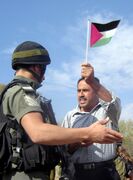 جندي إسرائيلي في مواجهة مع رجل يحمل علم فلسطين أثناء مظاهرات في بلعين.